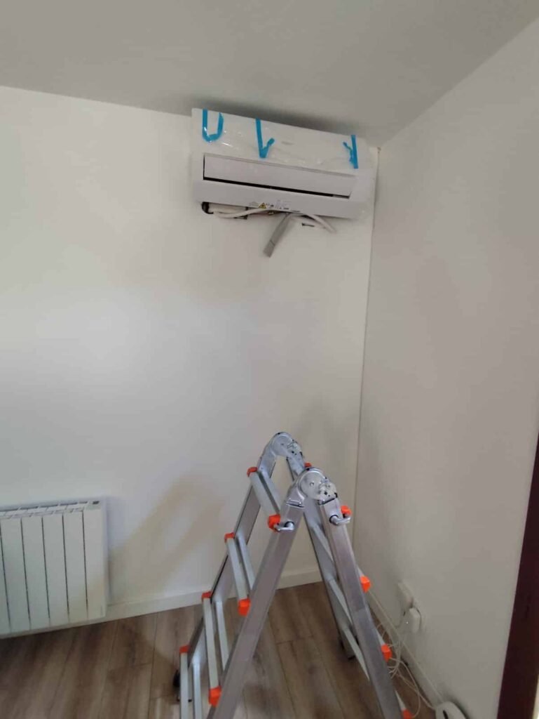 Unité intérieure murale d'un monosplit réversible posée en haut du mur dans un salon à Montgiscard